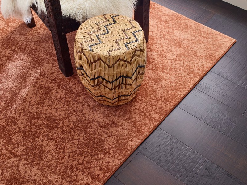 Room with dark hardwood flooring and an orange patterned rug - Carpet binding services from Korfhage Floor Covering in the Louisville, KY area