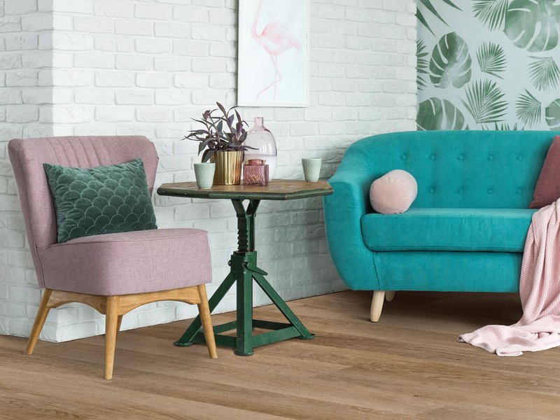 Teal couch and pink armchair in living room with wood-look luxury vinyl flooring from Korfhage Floor Covering in the Louisville, KY area