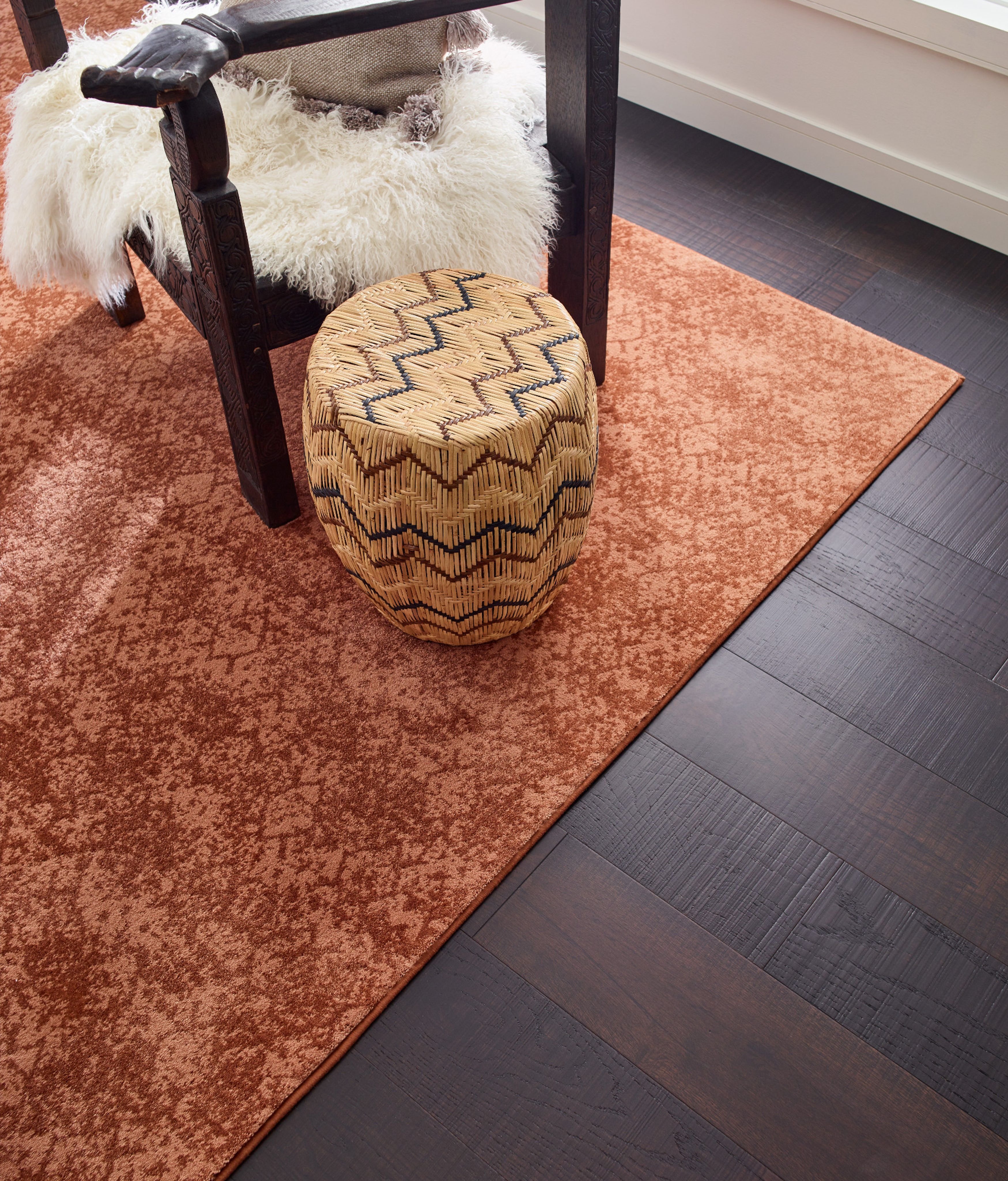 Room with dark hardwood flooring and an orange patterned rug - Carpet binding services from Korfhage Floor Covering in the Louisville, KY area